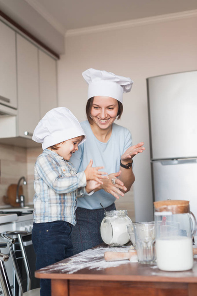 madre e hijo aplaudiendo mientras preparan la masa en la cocina
 - Foto, Imagen
