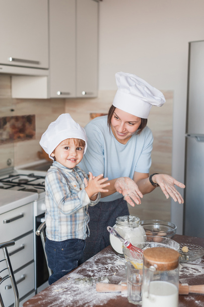 feliz joven madre y el niño preparando la masa en la cocina
 - Foto, imagen