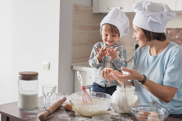 feliz hermosa madre e hijo preparando la masa en la cocina
 - Foto, Imagen