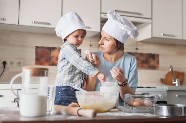 madre enseñando a su hijo cómo preparar la masa en la cocina
 - Foto, Imagen