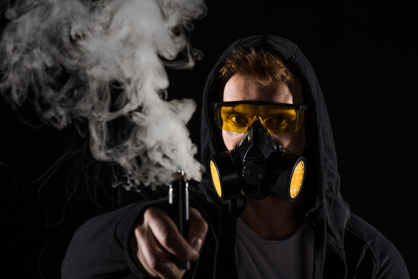 Man wearing protective filter mask activating electronic cigarette - Photo, Image