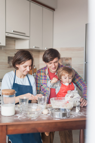 família jovem feliz preparando massa na cozinha bagunçada
 - Foto, Imagem