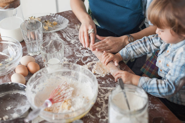 обрезанный снимок матери и ребенка, скатывающегося тесто для печенья
 - Фото, изображение