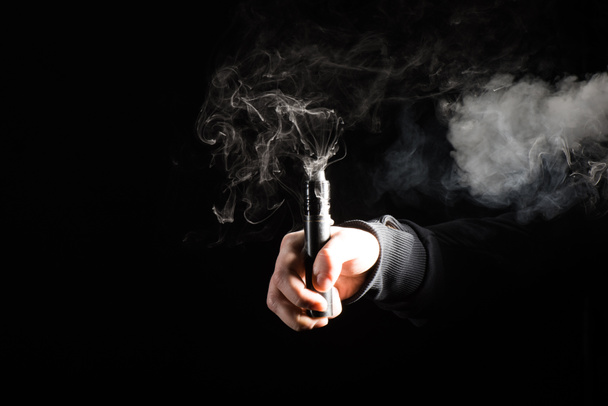 abgeschnittene Ansicht einer männlichen Hand, die elektronische Zigarette auf schwarzem Hintergrund aktiviert - Foto, Bild