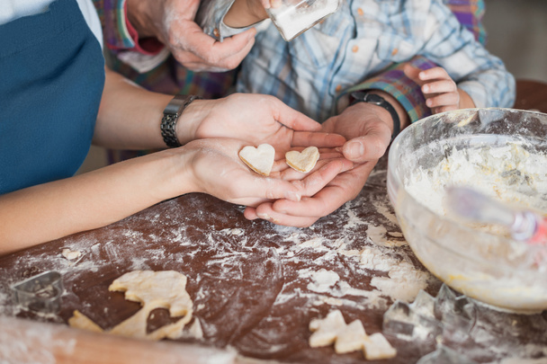 cropped shot of family preparing homemade cookies in shape of heart together - Foto, afbeelding