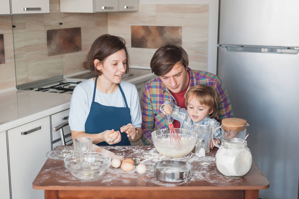hermosa familia joven preparando galletas caseras en forma de corazones
 - Foto, Imagen