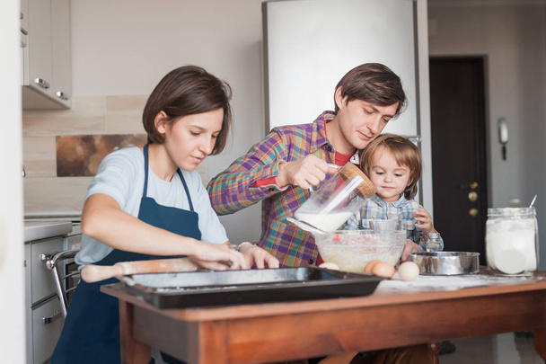 belle jeune famille préparant la pâte pour les biscuits faits maison
 - Photo, image