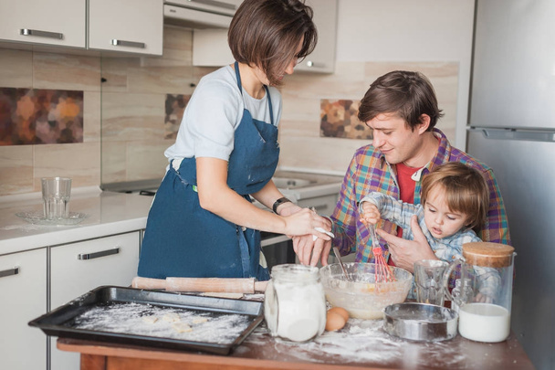 bela jovem família preparando biscoitos caseiros juntos
 - Foto, Imagem
