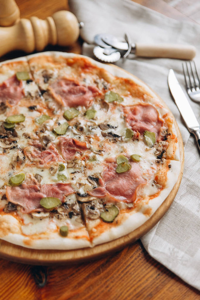 Nahaufnahme einer leckeren Pizza auf einem Holzschneidebrett mit Besteck  - Foto, Bild