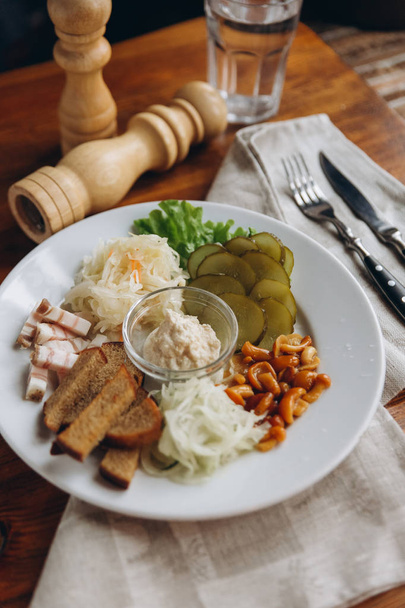 Assiette avec collations savoureuses et sauce au milieu et moulin à poivre, couverts sur serviette beige
 - Photo, image
