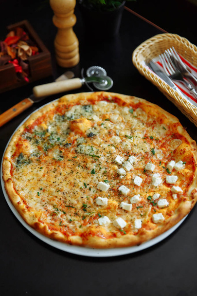 Pizza with feta, tomato sauce and herbs on white plate served on table - Photo, Image
