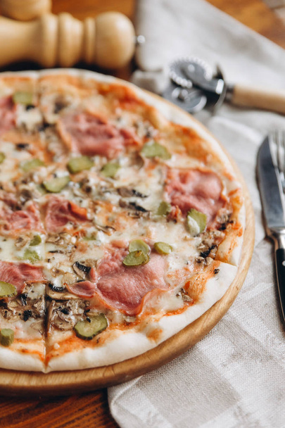 Vértes nézet ízletes pizza a fa vágódeszka, evőeszközök  - Fotó, kép