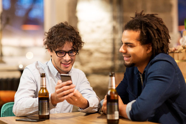 men with smartphone drinking beer at bar or pub - Photo, Image