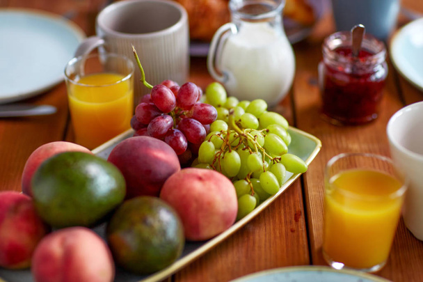 fruits, juice and other food on table at breakfast - Фото, изображение