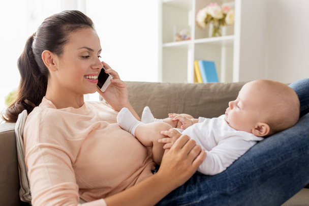mother with baby calling on smartphone at home - Foto, afbeelding