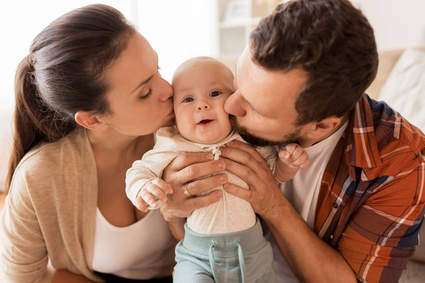 happy mother and father kissing baby at home - Fotoğraf, Görsel