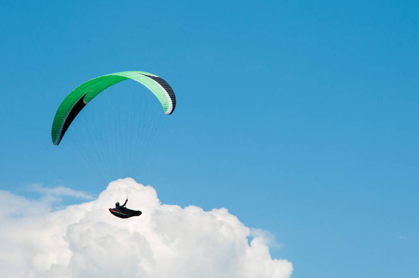 Alleen paraglider vliegen in de blauwe lucht tegen de achtergrond van wolken.  - Foto, afbeelding