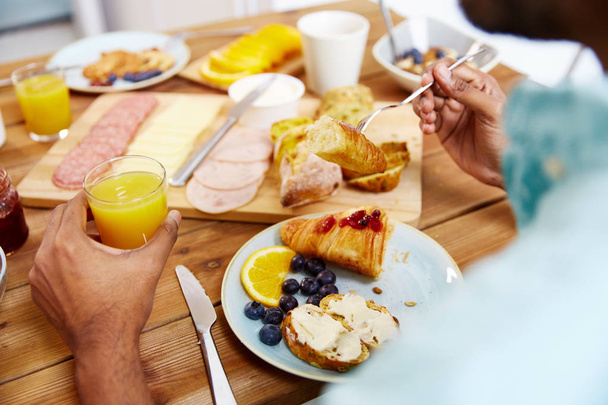close up of man eating croissant with orange juice - Foto, afbeelding