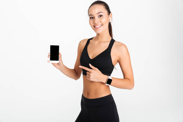 Portrait of a smiling asian fitness woman pointing finger - Foto, Imagen