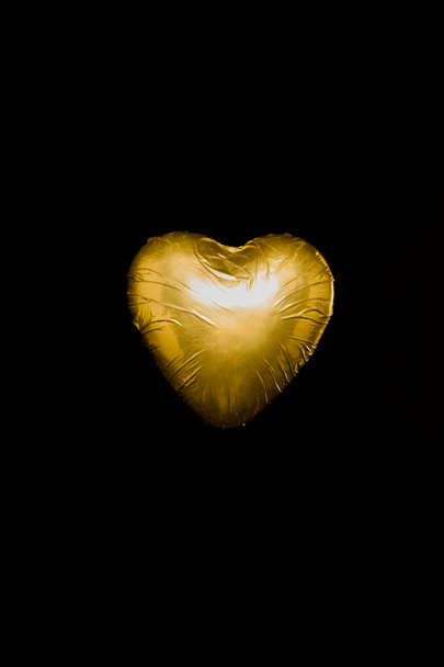 Sydämen muotoinen karkkia kultainen kääre eristetty musta
 - Valokuva, kuva