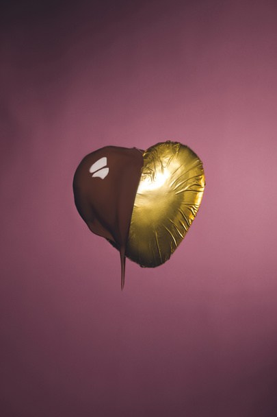 heart shaped candy in golden wrapper with liquid chocolate isolated on pink - Photo, Image