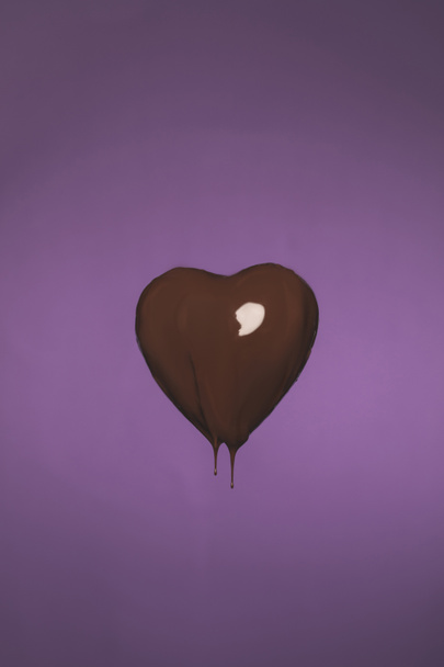 heart shaped candy with liquid chocolate isolated on purple - Photo, image