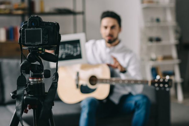 blogger musical sosteniendo notas y guitarra frente a la cámara
 - Foto, imagen
