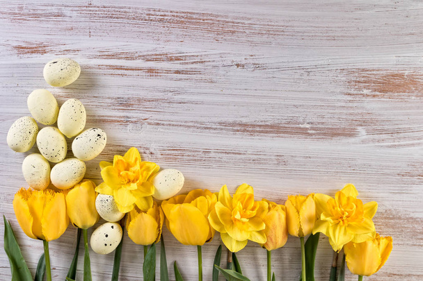 Pääsiäisen tausta keltaisilla kukilla ja pääsiäismunilla tekstillä
 - Valokuva, kuva