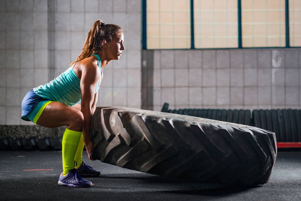 Woman athlete exercising with tire - Foto, afbeelding