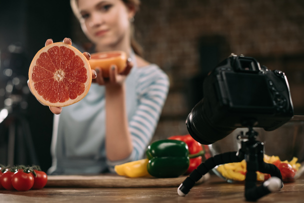 блогер молодої їжі, що показує половину грейпфрута на камеру
 - Фото, зображення