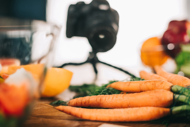 zanahorias maduras en mesa de madera con cámara sobre fondo borroso
 - Foto, Imagen