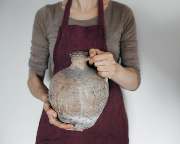 Молодая девушка держит глиняный кувшин
 - Фото, изображение