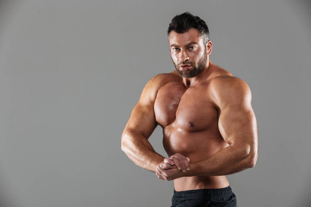 Portrait of a muscular confident shirtless male bodybuilder - Fotoğraf, Görsel
