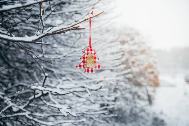 Brinquedo de Natal pendurado em uma filial coberta de neve no parque
. - Foto, Imagem