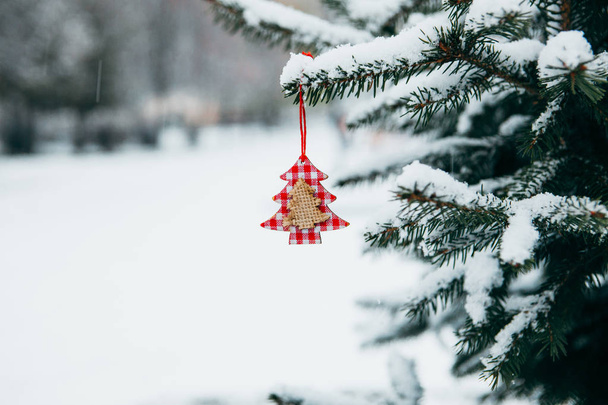 Χριστούγεννα παιχνίδι κρέμονται πάνω σε ένα κλαδί χιονισμένο στο πάρκο. - Φωτογραφία, εικόνα