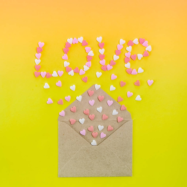 Sweets sugar candy hearts fly out of craft paper envelope and create word Love on the bright gradient background . Valentine day. love diversity concept. Gift, message for lover. Space for text - Foto, immagini