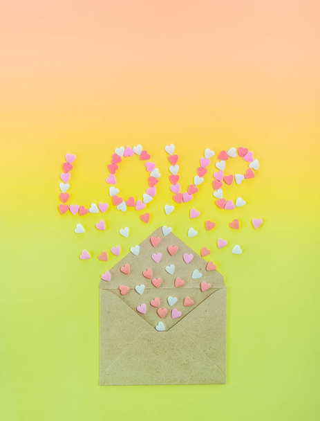Sweets sugar candy hearts fly out of craft paper envelope and create word Love on the bright gradient background . Valentine day. love diversity concept. Gift, message for lover. Space for text - Foto, immagini