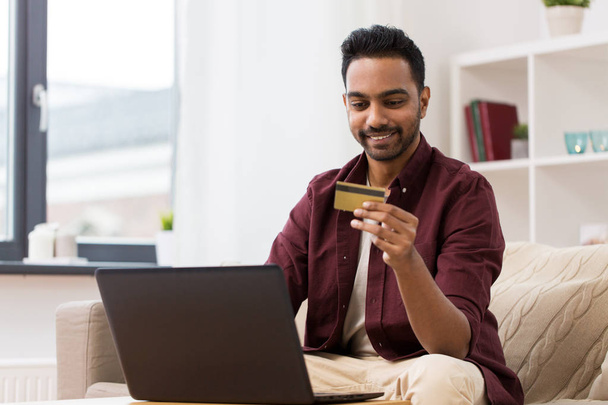smiling man with laptop and credit card at home - Fotó, kép