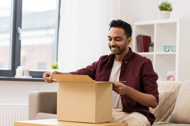 happy man opening parcel box at home - Фото, изображение