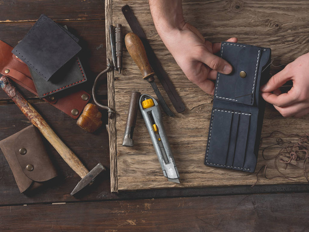 close-up of male hands sew leather wallet on wooden table - Foto, Imagem