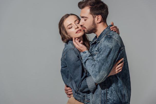 seductora pareja joven con los ojos cerrados abrazándose y tocándose aislados en gris
 - Foto, imagen
