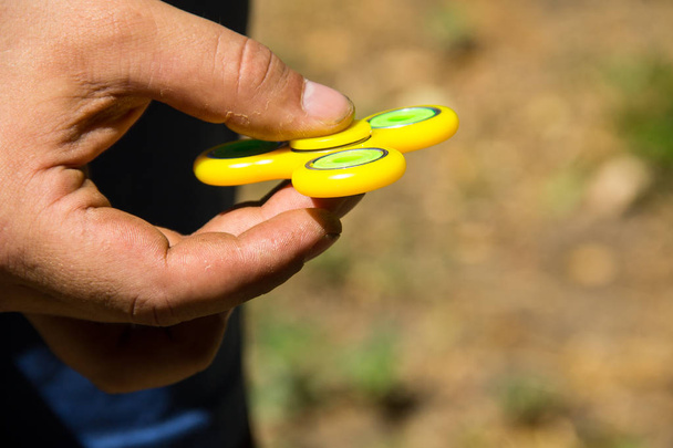 Man met fidget spinner stress verlichten van speelgoed buiten spelen - Foto, afbeelding