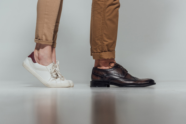 cropped shot of male and female legs in footwear with reflection on grey - Fotoğraf, Görsel