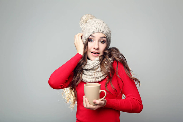 Beautiful young girl in hat and scarf holding cup of tea - Фото, зображення