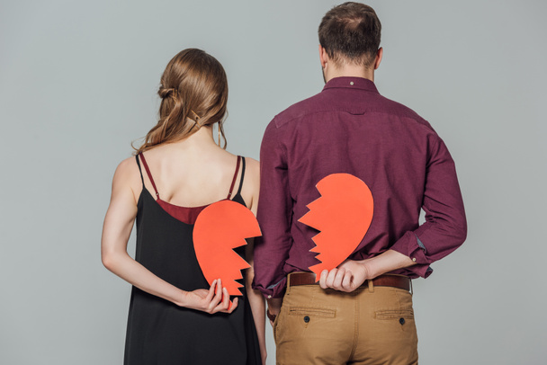 back view of young couple holding broken heart symbol isolated on grey   - 写真・画像