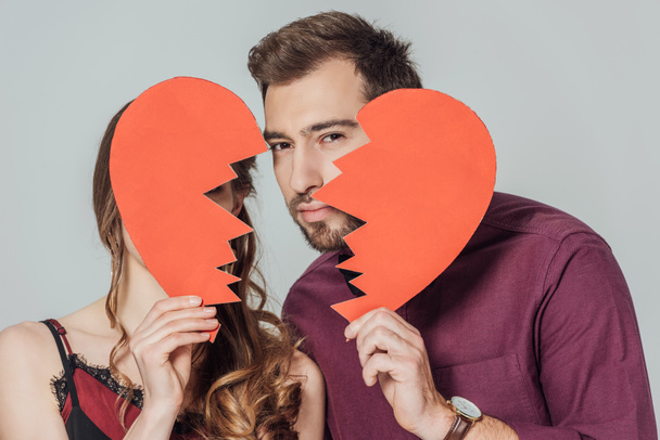 stylish young couple holding broken heart symbol isolated on grey  - Fotoğraf, Görsel