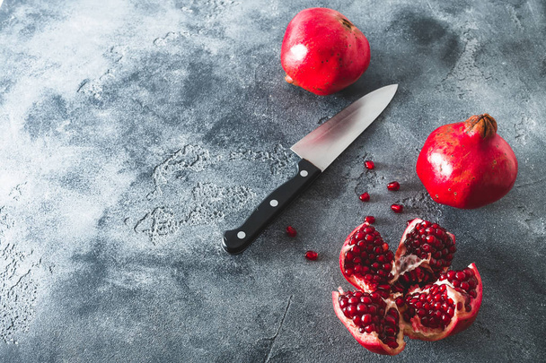 Červená granátová jablka a nůž na tmavém pozadí. Plochá ležel, horní pohled - Fotografie, Obrázek