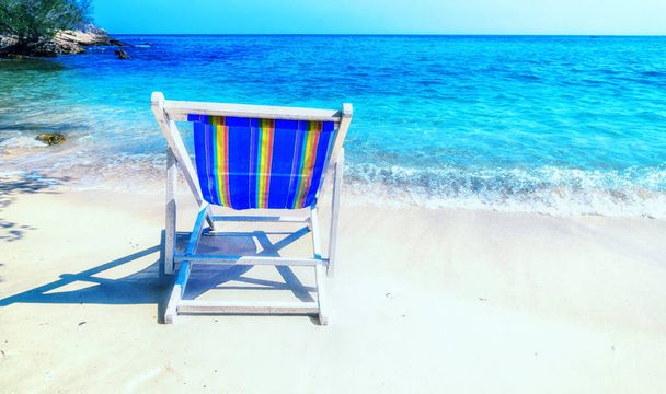 Chaise lounge luminoso en la arena en la orilla del mar
. - Foto, imagen