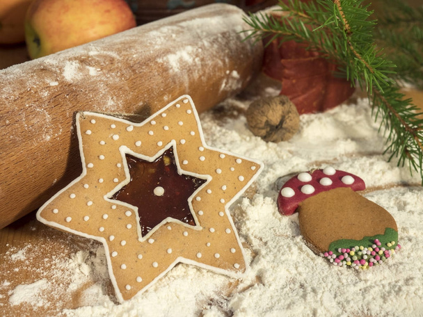 αστέρι και μανιτάρι - χριστουγεννιάτικο δέντρο gingerbreads σε διάφορα σχήματα που βρίσκεται πάνω στο τραπέζι, όπου ήταν κατασκευασμένα από αλεύρι και αρωματικά πρόσθετα, γιορτινή ατμόσφαιρα, πικάντικο άρωμα και μελόψωμο μπαχαρικών - Φωτογραφία, εικόνα