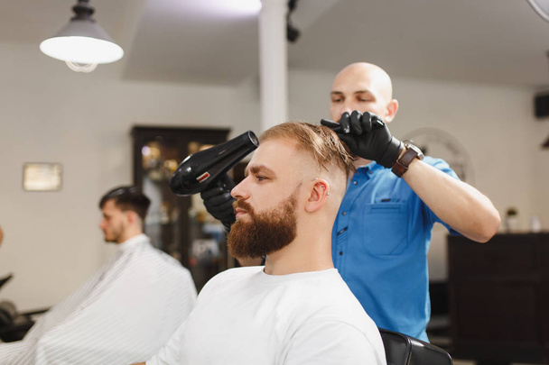 Αρσενικό επαγγελματία κομμωτή που εξυπηρετούν πελάτη, στέγνωμα μαλλιών με h - Φωτογραφία, εικόνα